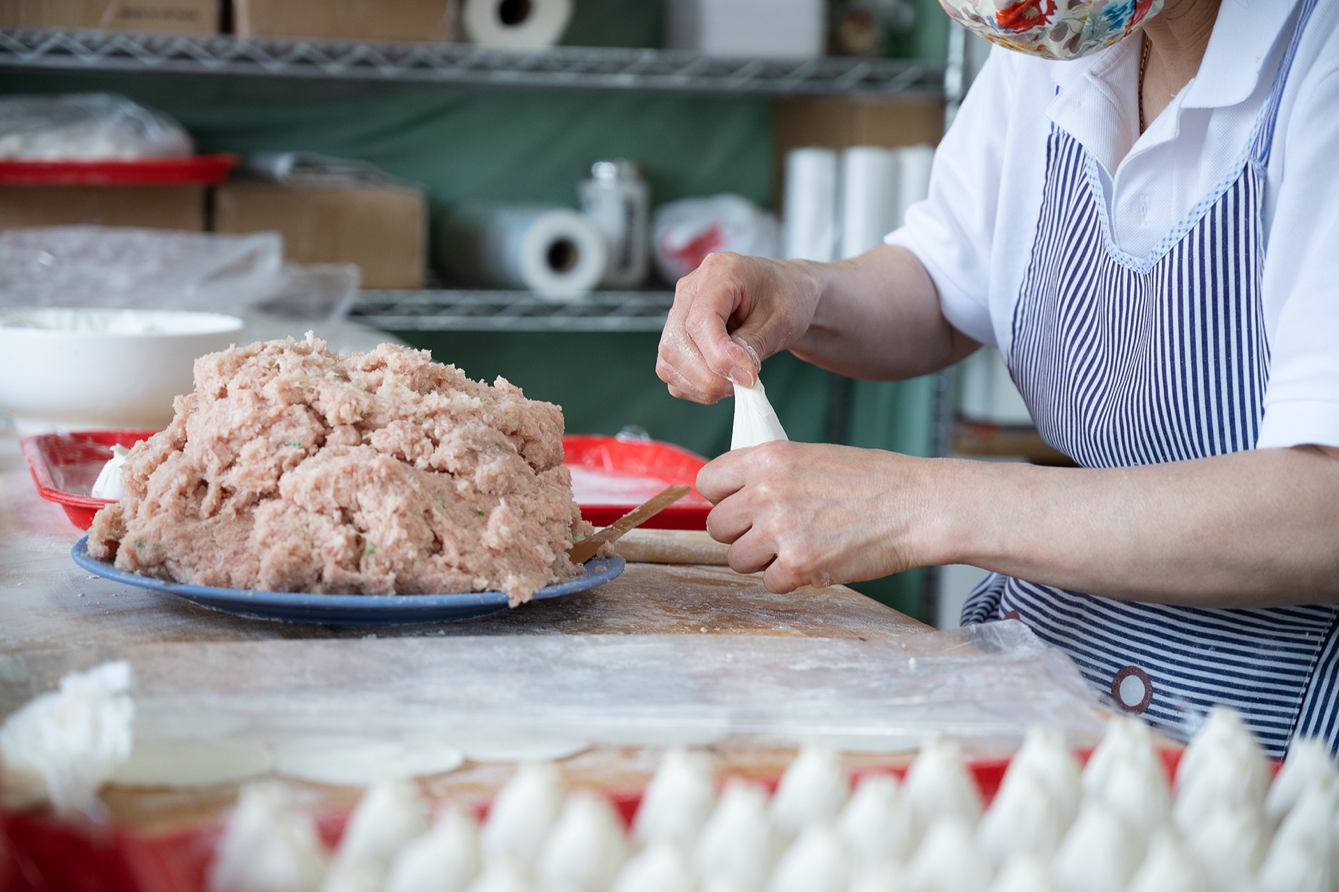 Close-up of skilled hands pinching and pleating a xiaolongbao wrapper