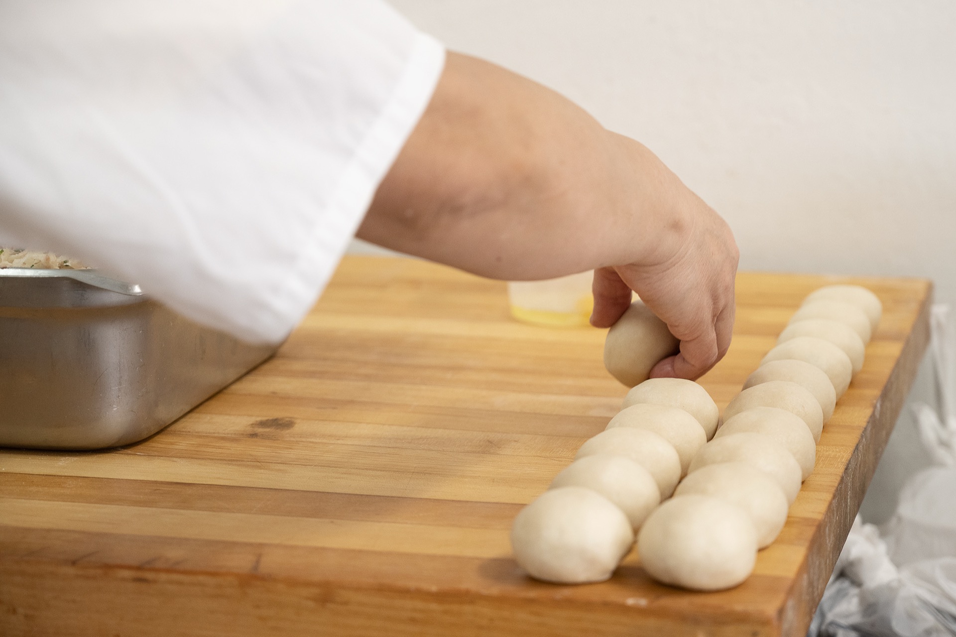 Chef arranging uniform dough balls in a row for rolling
