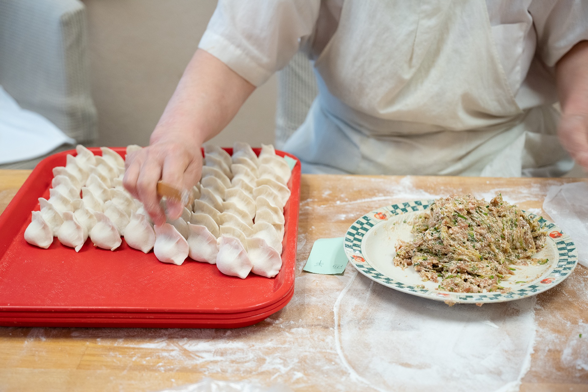 Red tray packed with rows of hand-folded crescent dumplings