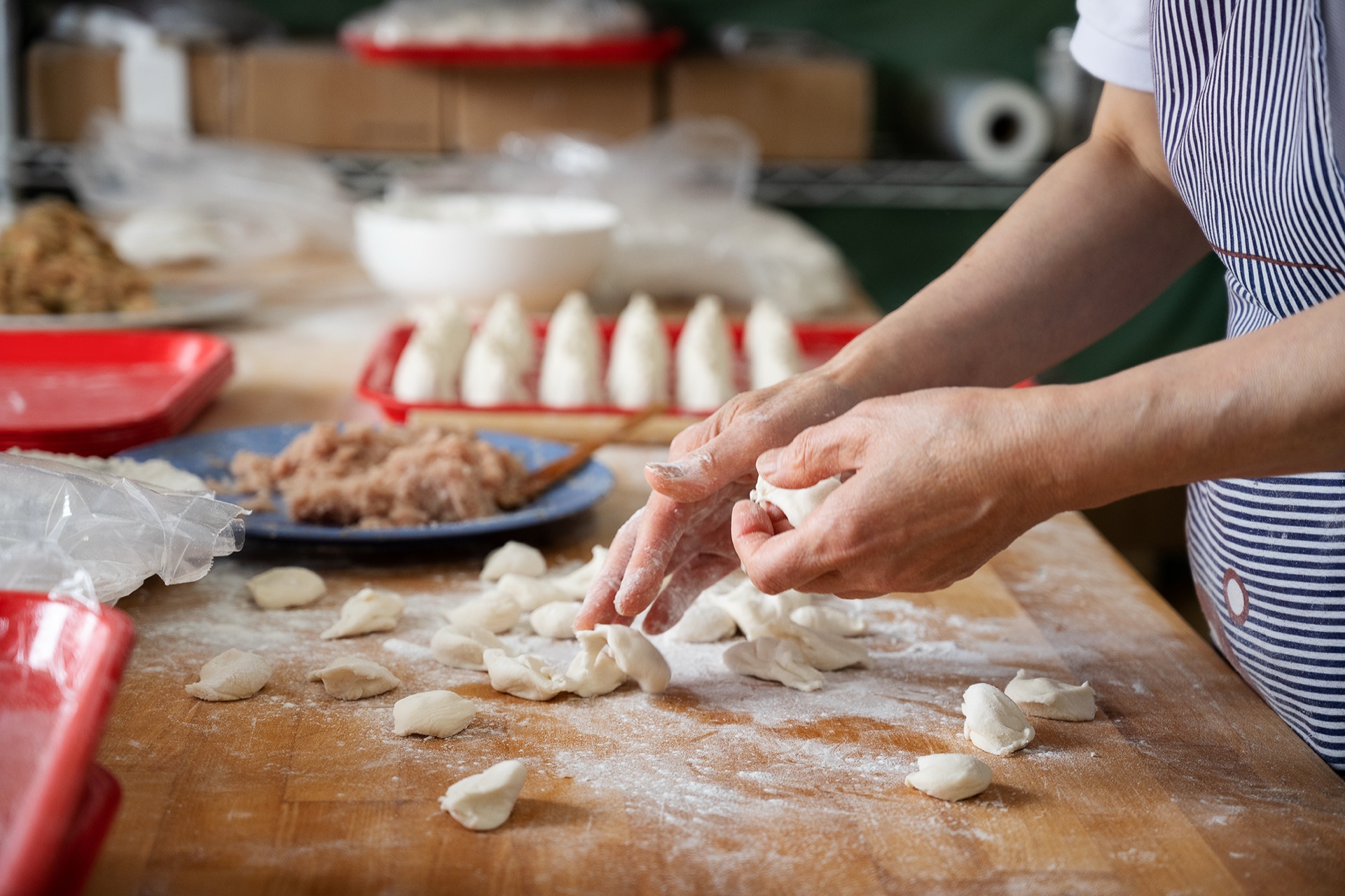Hands folding dumplings on a flour-dusted cutting board